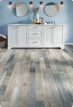 A modern bathroom with a white vanity, gray and blue wooden flooring