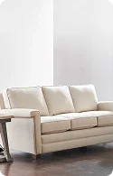 A modern, light-colored sofa with three plush cushions