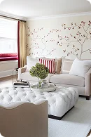 Cozy living room featuring a white sofa, tufted ottoman
