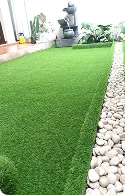 Lush artificial grass lawn bordered by smooth pebbles