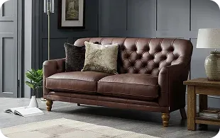 A brown leather tufted sofa with two decorative pillows