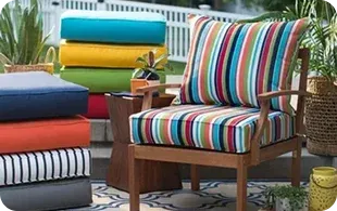 A striped outdoor chair beside colorful cushions stacked vertically