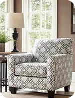 A stylish grey patterned armchair in a bright room with a lamp