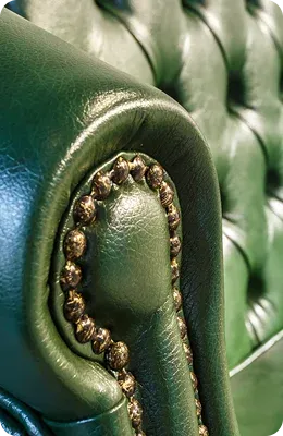 Close-up of a green leather sofa armrest adorned
