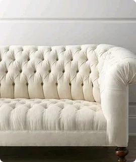 Elegant cream tufted sofa with a curved arm and wooden legs