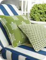 Two decorative outdoor pillows on a blue and white striped lounge chair