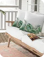 A cozy porch seating area featuring cushions with tropical leaf prints