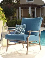 A stylish blue outdoor chair with a decorative green and white throw pillow