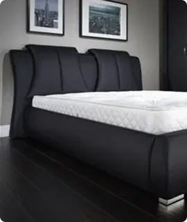 Black upholstered bed with a white mattress