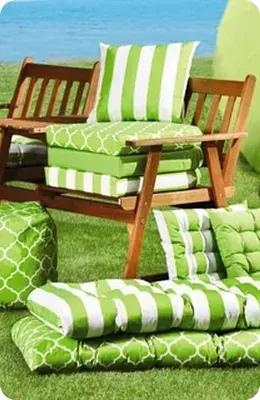 Green and white cushions on a wooden bench outdoors